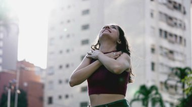 Neşeli kadın kollarını açıp güneşin sıcağında güneşleniyor, doğanın güzelliğini takdir ediyor ve hayata şükrediyor.