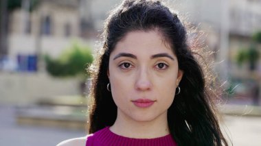 Tarafsız yüzlü genç bir kadın şehir parkında kameraya bakıyor. Bir kadın milenyum 30 'lu yaşlarda yakın çekim yüzü.