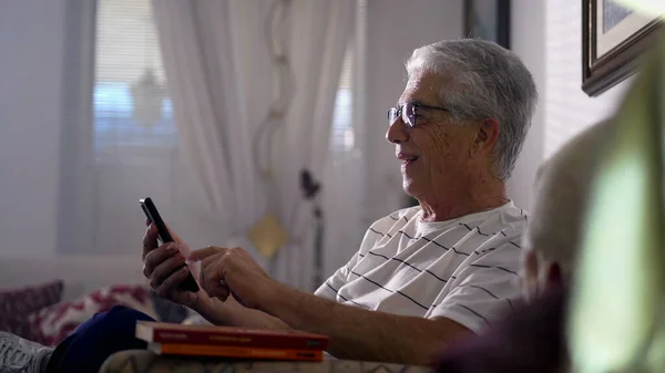 Candid Happy Elderly Man Using Cellphone Home Seated Couch Gray — Stock Photo, Image