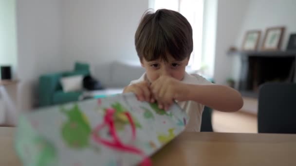 兴奋的孩子在家里打开礼物 一个小男孩打开礼物 撕破了纸 急切地期待着奖品 — 图库视频影像
