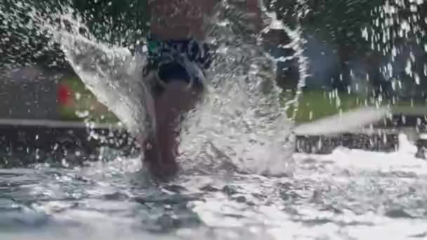 夏の暑い日にパブリックプールで楽しむ子供たちは スローモーションで水滴が飛び散り プールサイドで出かけます — ストック動画