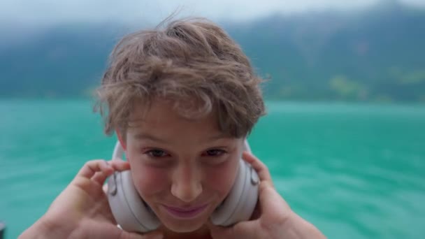 Портрет Красивого Молодого Хлопчика Знімає Навушники Посміхається Камери Стоячи Озеро — стокове відео
