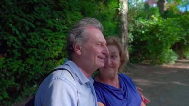 Fröhliches Seniorenpaar Genießt Sonnigen Tag Auf Parkbank Ehemann Legt Arm — Stockvideo