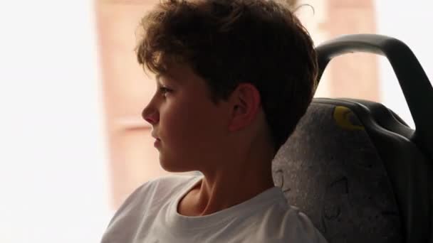 小男孩坐公共汽车旅行的概况 凝视着路过的风景 坐车旅行时不断地做梦的十几岁的孩子 — 图库视频影像