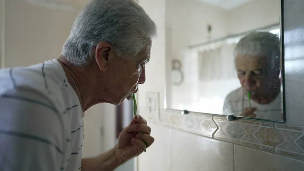 Homem Sênior Escovando Dentes Frente Espelho Banheiro Cena Doméstica Casual — Fotografia de Stock