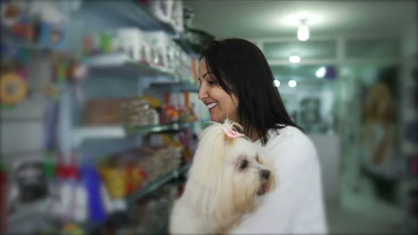 Woman Holding Small Dog While Browsing Pet Products in Store