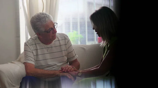 Mature Woman Offering Support to Elderly Friend in candid scene at home sitting on couch. Comforting scene Between Mature Friends During Hard Times, Holding Hands showing empathy