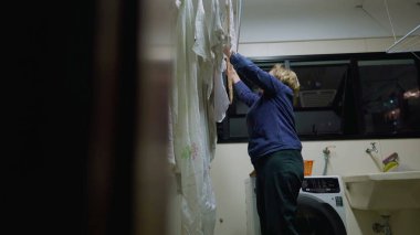 Kurutma sehpasında çamaşır yıkayan yaşlı bir kadın, günlük hayata bir bakış. Emekli yaşlı bayanın evdeki rutin sahnesi. Samimi ve otantik