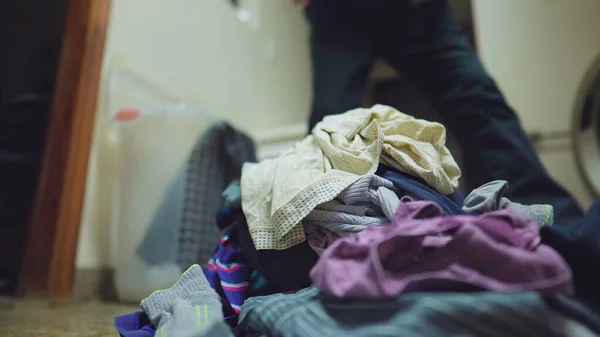 洗濯をする人の国内シーン 家のルーチンを行う背景にぼやけた人と一緒に床に積み上げ服のクローズアップ — ストック写真