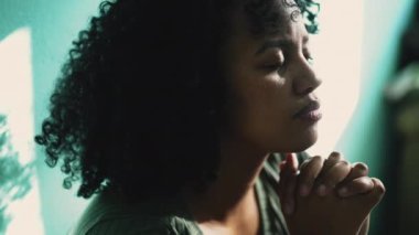 Umut dolu Brezilyalı genç bir kadın evde dua ediyor. Afrika kökenli bir Güney Amerikalı.
