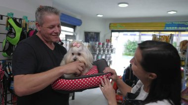 Küçük Köpeği Tutan Mutlu Hayvan Müvekkilleri. Kadın İşletme Sahibi Shih-Tzu 'yu Bakım Banyosundan sonra Erkeğe Veriyor