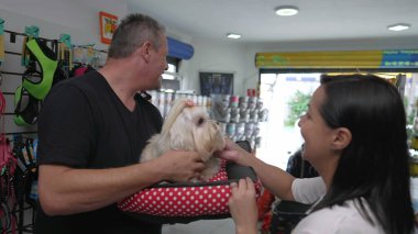 Küçük Köpeği Tutan Mutlu Hayvan Müvekkilleri. Kadın İşletme Sahibi Shih-Tzu 'yu Bakım Banyosundan sonra Erkeğe Veriyor