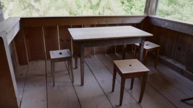 Köy ahşap balkonu, yaşlanmış masası ve çiftlik evinde sandalyeleri var.