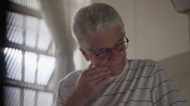 Endişeli Yaşlı Adam pencerenin kenarında endişeli endişeli duruyor. Pişman gri saçlı insan geçmişteki hataları düşünüyor.