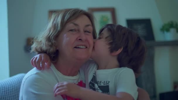 高齢のおばあちゃんへのキスで愛を表現する子供 リトルボーイのシニアファミリーメンバーへの心からのキス — ストック動画