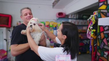 Evcil hayvan dükkânı sahibi, küçük köpeği bakkalda tımar ettikten sonra müşteriye geri veriyor.