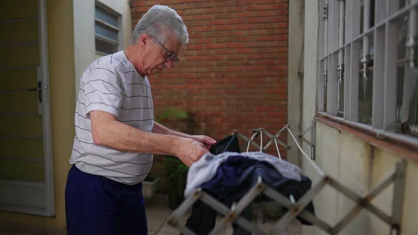 老人把衣服放在自家后院的衣架上晾干 独立的老年人每周在临时寒舍做家务 — 图库照片