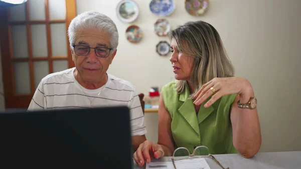 Troubled Elderly Couple Dealing with Financial Issues in front of laptop computer in Kitchen