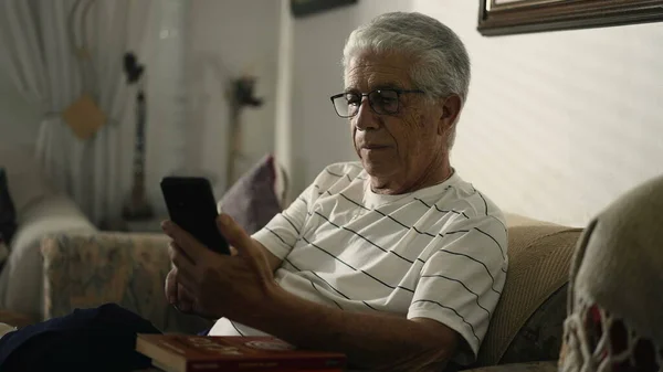 Starszy Mężczyzna Gapiący Się Telefon Komórkowy Siedzący Kanapie Domowej Niepokojącym — Zdjęcie stockowe