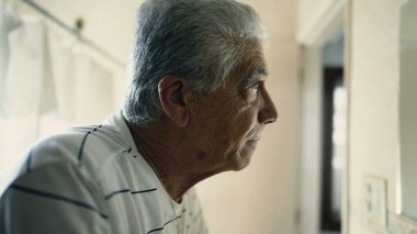 Dramatik yaşlı adam banyoda dikilip aynanın yansımasına bakıyor. Yaşlılık deneyimi yaşıyor.