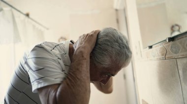 Yaşlı bir adam güne banyoda dikilip aynanın önünde kendi yansımasına bakarak başlıyor.