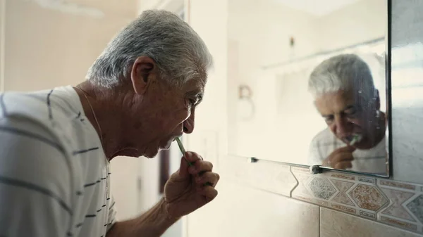 トイレの鏡で自分自身の反射を見つめながら 鏡にブラッシングするシニア朝のルーチン 歯科衛生 初日からお年寄り — ストック写真