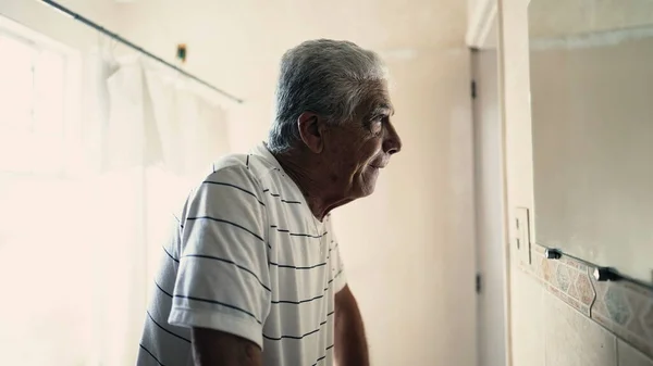 トイレに立っている抑圧された上級男性は 鏡に映った自分自身の反射を見つめている 悲しみと後悔に苦しんでいる高齢者 — ストック写真