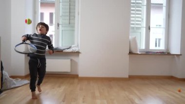 Yükselen Tenis Yıldızı: Boş Apartman Odasında Çocuk Tenisi Oyunu, aile yeni evine taşınıyor. Küçük çocuk duvara raketle vurarak egzersiz yapıyor.