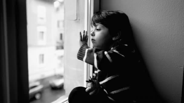 忧心忡忡的孩子靠在窗前想出去 被束缚的孩子感到厌倦和孤独 黑白戏剧中的社会隔离童年 — 图库视频影像