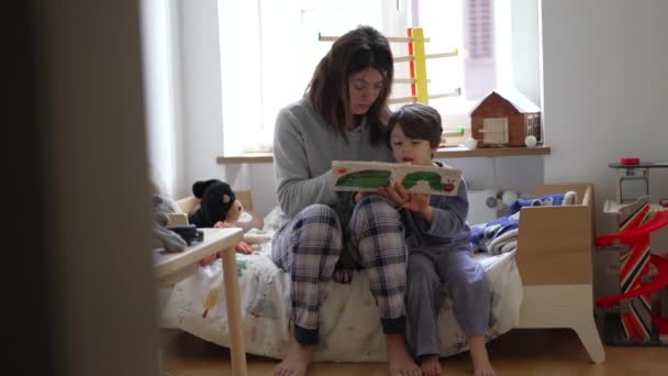 マザーリーディングストーリーの本格的なベッドルームシーン リトルソン ママと本との親子の瞬間 — ストック動画