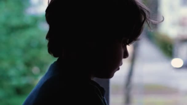 メランコリックの落ち込んだ子供は 静かな絶望の中にまだ座っているアパートの建物の窓に座っています うつ病と悲しみを示す悲しい子供 — ストック動画