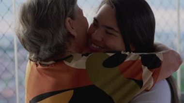 Torun ve büyükannenin çok nesilli kucaklaşmasının yürek ısıtan aile buluşması. Çeşitli Asyalı Yetişkin Kız Beyaz Kıdemli Kadını Sardı