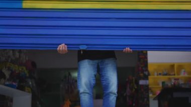 Small Shop 'un yerel sahibi, kaldırım kenarındaki garajı açıyor.