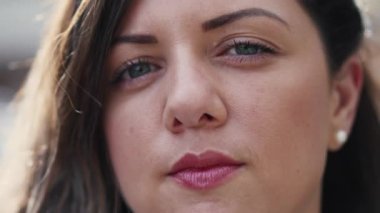 Dışarıda dik dik bakan 30 'lu yaşlarda bir kadının portresi. Kendine güveni olan birinin yakın çekim yüzü.