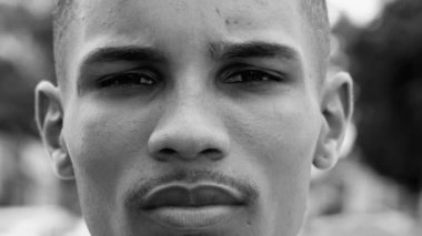 Ciddi bir siyah adam dramatik tek renkli siyah beyaz kameraya bakıyor. Sert, dışa dönük, aynı görüşte biri.