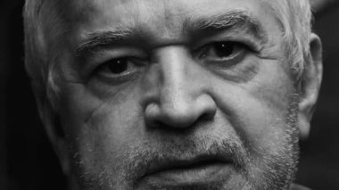 Tek renkli siyah-beyaz fotoğrafçılıkla yakından çekilmiş buruşuk yaşlı bir adamın dramatik portresi sert endişeli bir ifadeyle kameraya bakıyor.