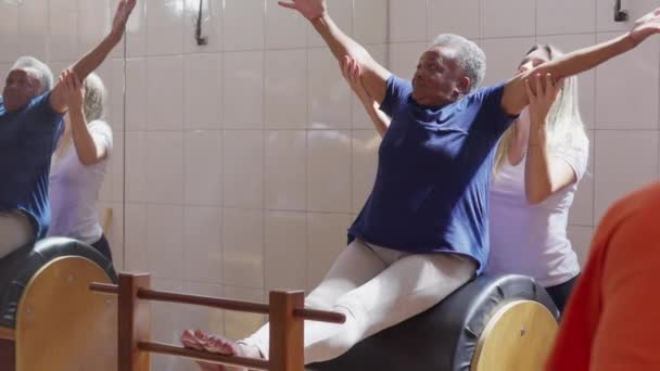 女普拉提教师帮助一名黑人老年妇女在日常锻炼中伸展身体 — 图库视频影像