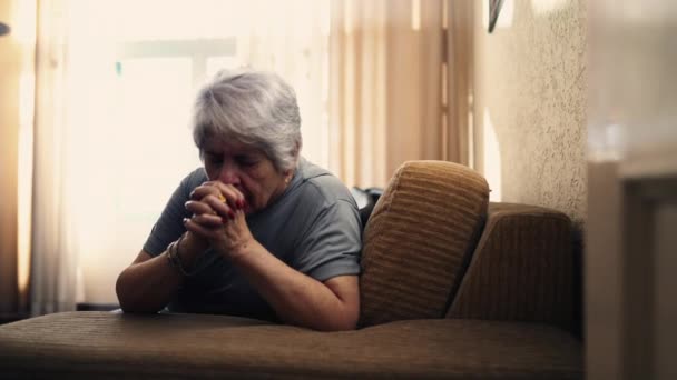 真正的白种人老年女性在家祈祷 老人双手紧握 坐在沙发上 奉献和信仰的墓穴 — 图库视频影像