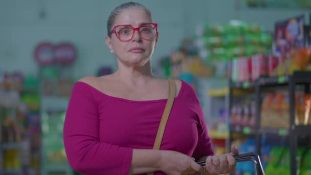 艰难时期 妇女提着篮子站在杂货店里 中年妇女消费者与通货膨胀和超级市场内的困难作斗争 — 图库视频影像