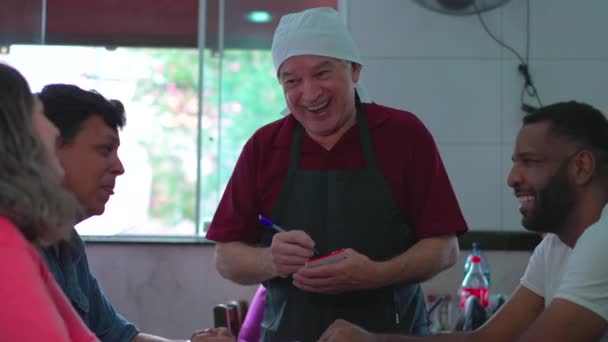 Счастливый Пожилой Официант Принимает Заказы Группы Клиентов Ресторане — стоковое видео