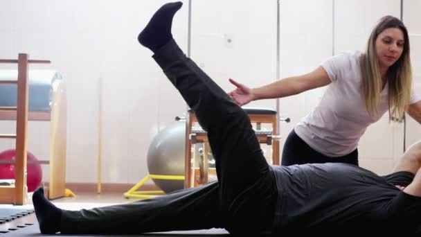 Инструктор Пилатесу Тренирующая Человека Лежащего Полу Упражнений Мячом — стоковое видео