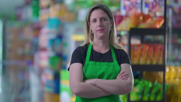 杂货商店中性表达的女性员工 有胳膊交叉 站在超级市场的门廊内 看相机 职业概念 — 图库视频影像