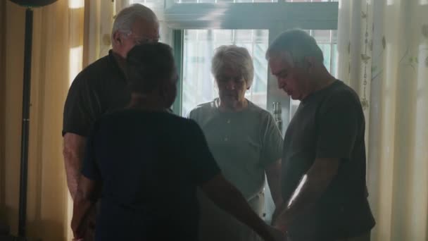 自宅で4人の高齢者 PrayerとD Devotionに従事する高齢者の候補グループ 光の光が輝く窓に立って — ストック動画