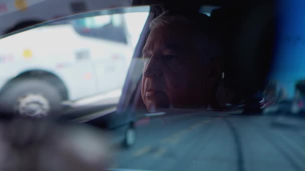 市内道路を走行中のリアビューミラーの反射を通して見たドライバー 高齢者ディルビング車 — ストック動画
