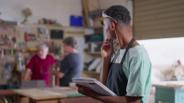 Jovem Aprendiz Negro Oficina Carpintaria Tomando Notas Bloco Notas Vestindo — Vídeo de Stock
