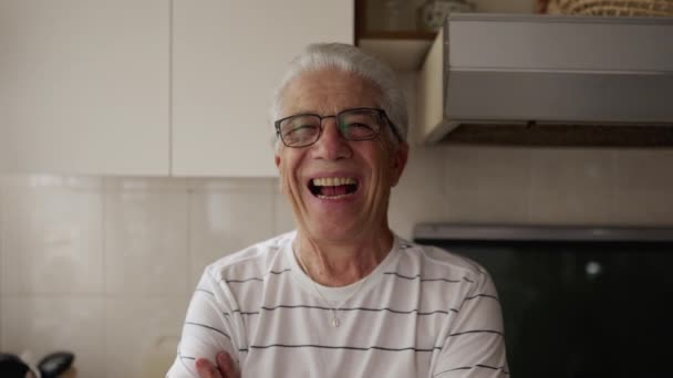 笑って笑って笑いながら 腕で自宅のキッチンに立っているジョイフルな老人 — ストック動画