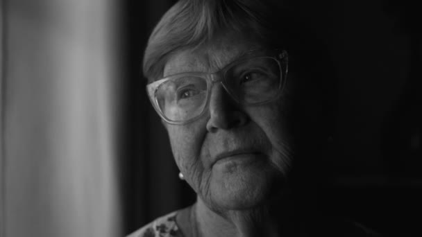 Starsza Kobieta Kontemplująca Dramatycznej Monochromatycznej Scenie Wychodząca Przez Okno Czerni — Wideo stockowe