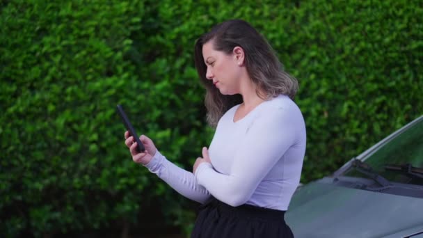 Kobieta Sprawdzająca Telefon Komórkowy Opierająca Się Maskę Samochodu Ulicy Osoba — Wideo stockowe