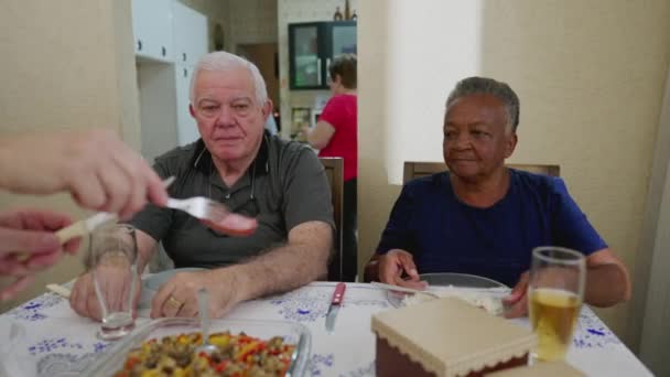 一群老年朋友聚在一起吃午饭 给一位黑人老年妇女端食物 — 图库视频影像