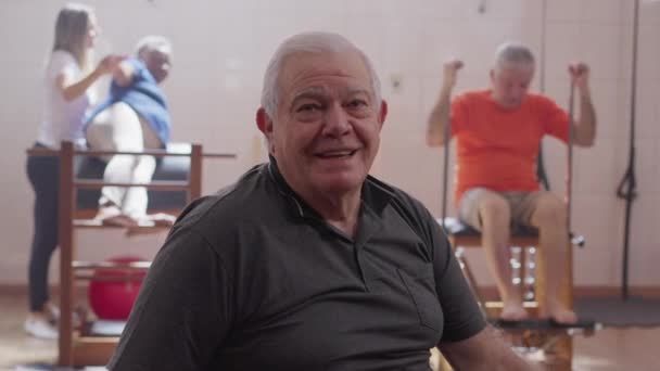 Pilates Dersinde Arka Planda Yaşlı Insanlarla Gülümseyen Mutlu Bir Kıdemli — Stok video